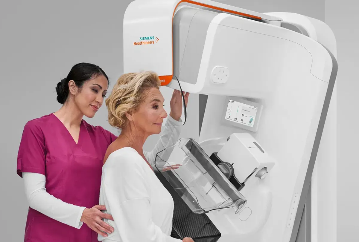 Técnica em radiologia posicionando a paciente no mamógrafo digital Siemens Healthineers